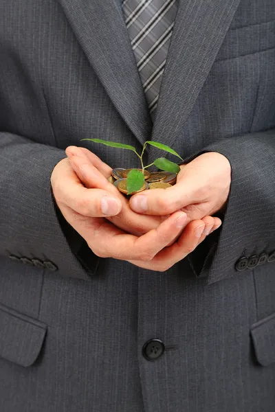 Jovem empresário com moedas e planta isolada no whit — Fotografia de Stock