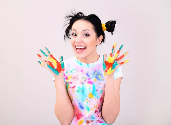 Young pretty painter with hands in paint, on gray background — Stock Photo, Image