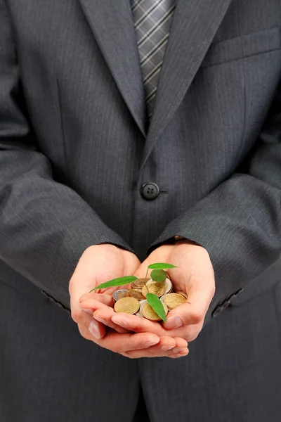 Młody biznesmen z monet i roślin na białym tle na Zielone Świątki — Zdjęcie stockowe