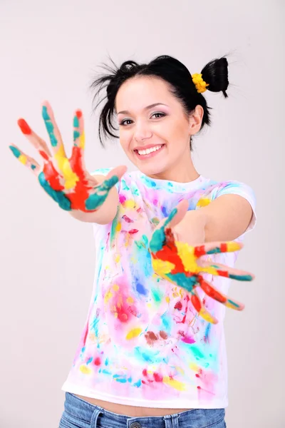 Young pretty painter with hands in paint, on gray background — Stock Photo, Image