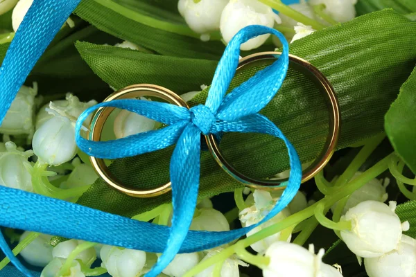 Anéis de casamento amarrado com fita no fundo da flor — Fotografia de Stock