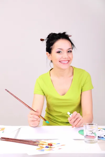 Beautiful young woman painter at work, on color background — Stock Photo, Image