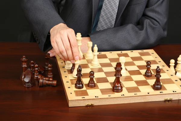 Young business man playing chess on black background — Stock Photo, Image