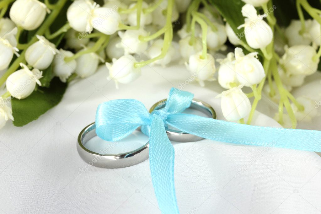 Wedding rings tied with ribbon on light gentle background