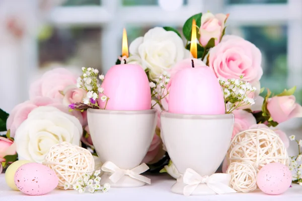 Easter candles with flowers on window background — Stock Photo, Image