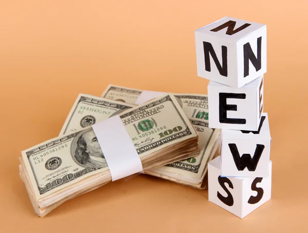 Dokument white paper kostky označen "news" s penězi na béžové pozadí — Stock fotografie