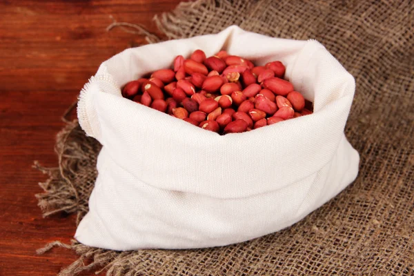 Peanuts in sack on wooden background — Stock Photo, Image