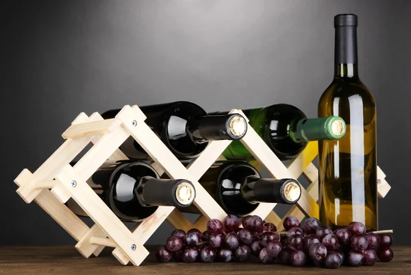 Botellas de vino colocadas sobre soporte de madera sobre fondo gris — Foto de Stock