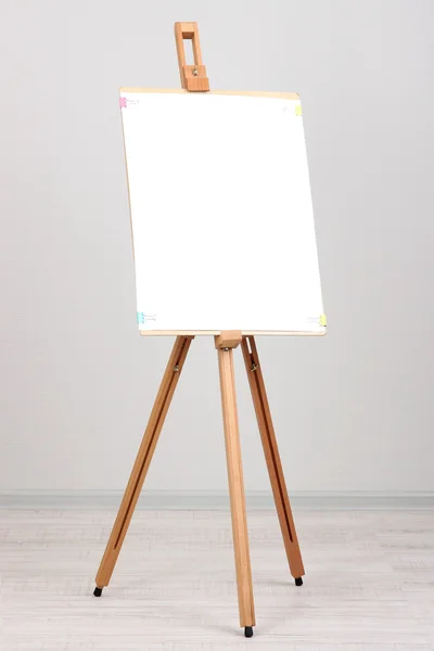 Wooden easel with clean paper in room — Stock Photo, Image