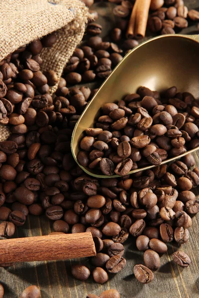 Coffee in sack and scoop on wooden table — Stock Photo, Image