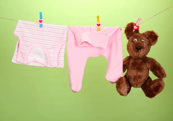 Baby clothes hanging on clothesline, on color background — Stock Photo, Image