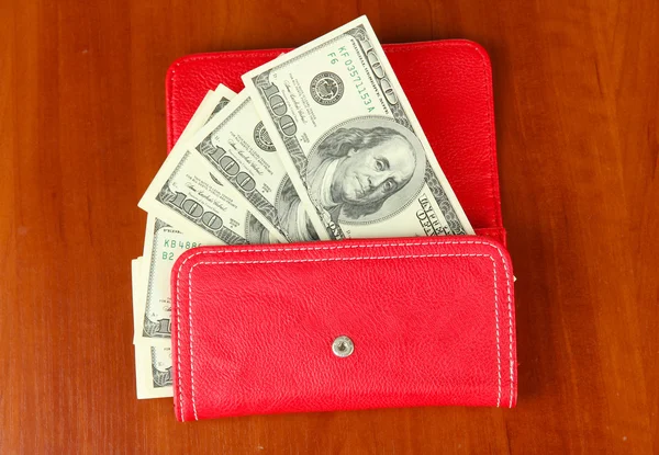 Purse with hundred dollar banknotes, on wooden background — Stock Photo, Image