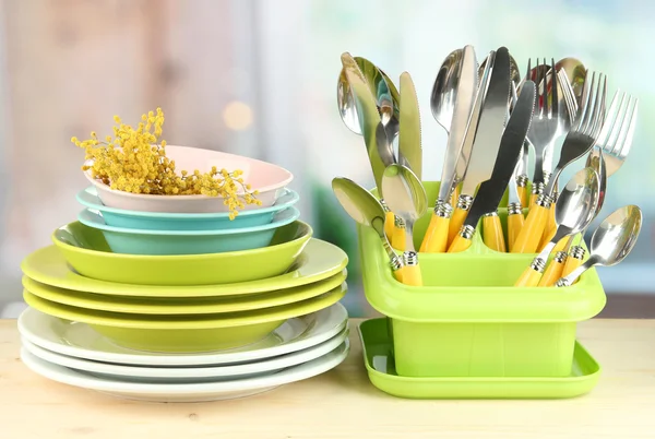 Placas, garfos, facas, colheres e outros utensílios de cozinha sobre fundo brilhante — Fotografia de Stock