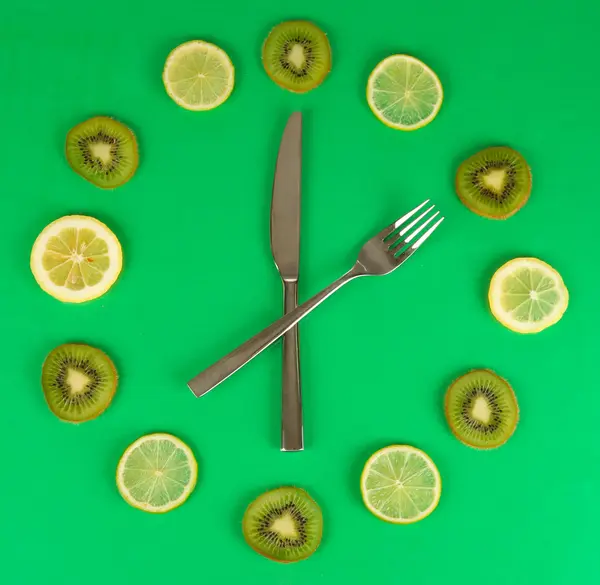 Reloj hecho de kiwi, lima y rodajas de limón, sobre fondo de color —  Fotos de Stock