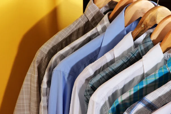 Mannen shirts op hangers op gele achtergrond — Stockfoto