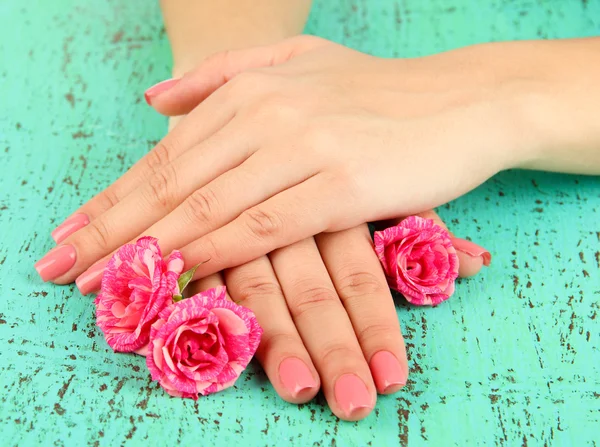 Woman hands with pink manicure and flowers, on color background — Stock Photo, Image