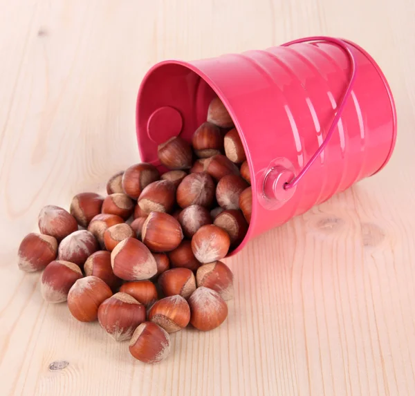 Overturned bucket with hazelnuts on wooden background — Stock Photo, Image