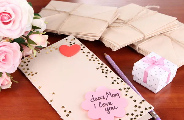 Writing letter of congratulations to mother's Day on wooden table close-up — Stock Photo, Image