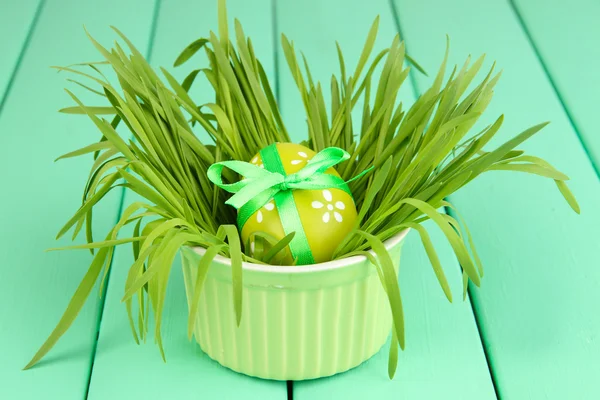 Ovo de Páscoa na tigela com grama na mesa de madeira verde fechar — Fotografia de Stock