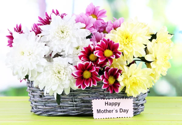 Букет красивых хризантем в плетеной корзине на столе на ярком фоне — стоковое фото