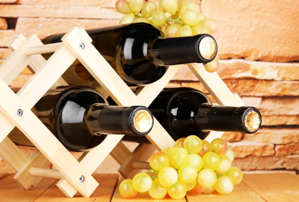 Garrafas de vinho colocadas no suporte de madeira no fundo da parede de pedra — Fotografia de Stock