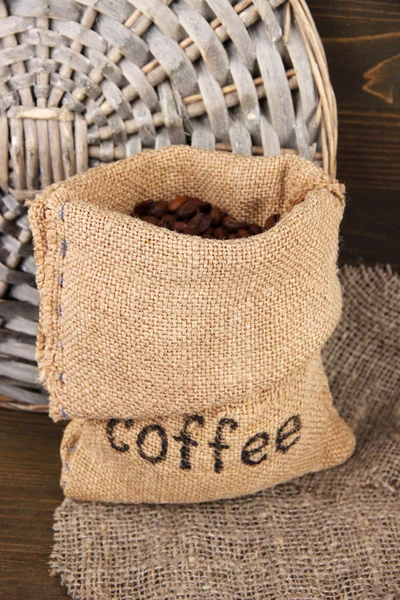 Coffee beans in sack on wooden background — Stock Photo, Image