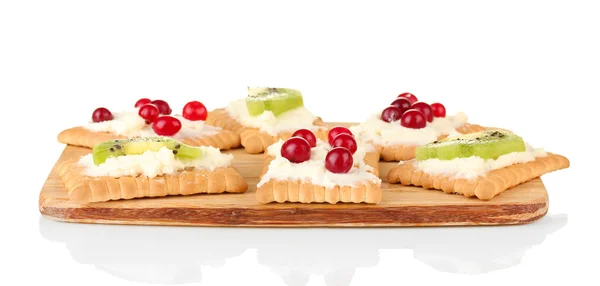 Lekkere canapeetjes met kaas, kiwi en cranberry, op snijplank, geïsoleerd op wit — Stockfoto