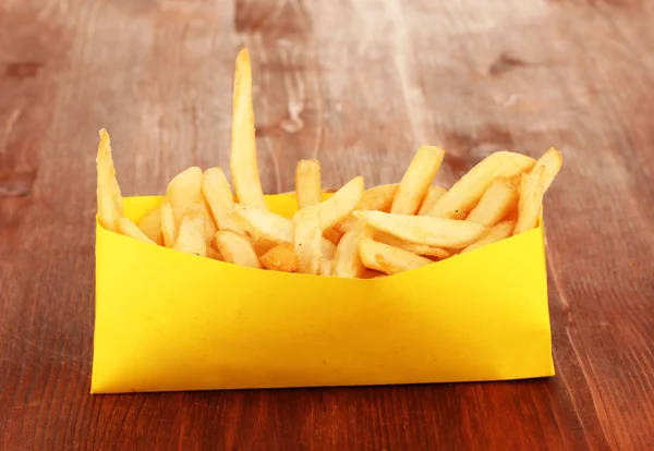 Pommes frites i papperspåse på träbord närbild — Stockfoto
