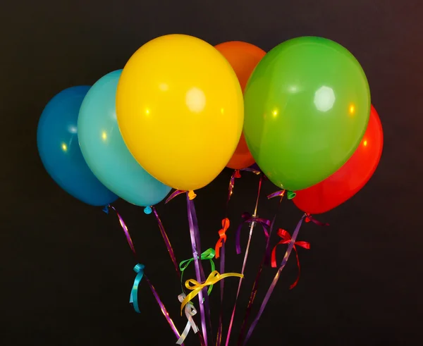Färgglada ballonger med band på mörk bakgrund — Stockfoto