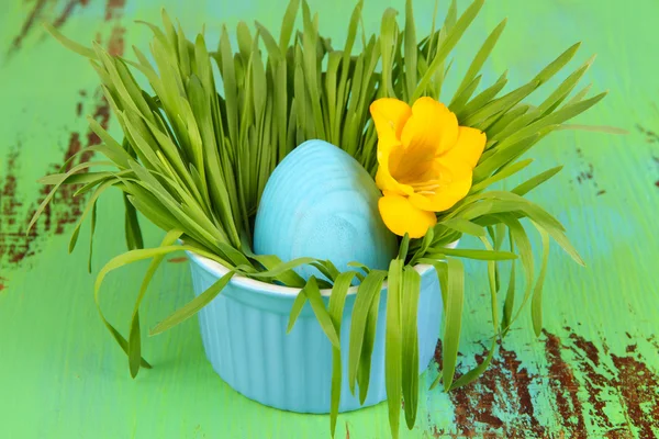 Osterei in Schüssel mit Gras auf grünem Holztisch in Großaufnahme — Stockfoto