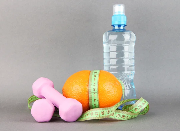 Naranja con cinta métrica, mancuernas y botella de agua, sobre fondo de color —  Fotos de Stock