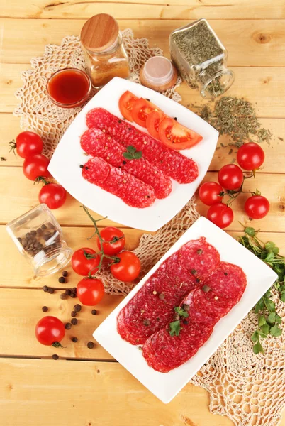 Leckere Salami auf Tellern auf Holztisch in Großaufnahme — Stockfoto