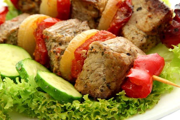 Tasty grilled meat and vegetables on skewers on plate, close up — Stock Photo, Image