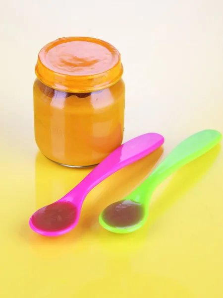 Baby food with weaning spoons on yellow background — Stock Photo, Image