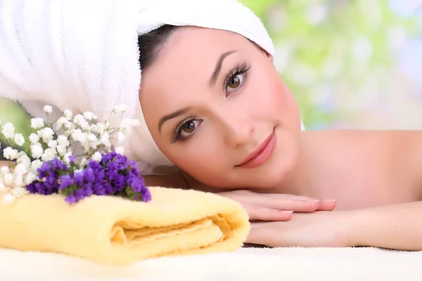 Krásná mladá žena s ručníkem na hlavě na světlé pozadí — Stock fotografie