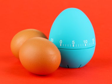 Mavi yumurta zamanlayıcı ve renkli arka plan üzerinde yumurta