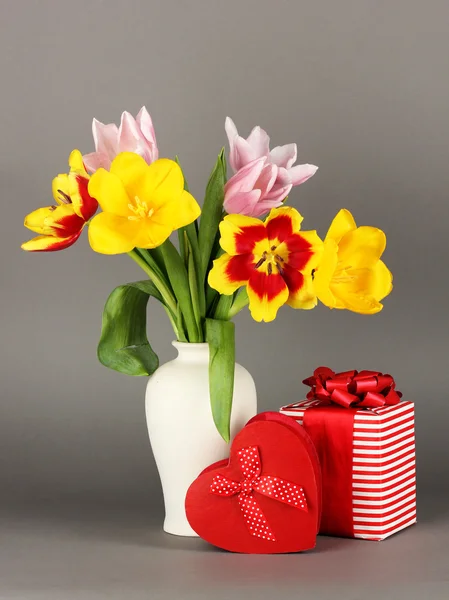 Hermosos tulipanes en cubo con regalos sobre fondo gris —  Fotos de Stock