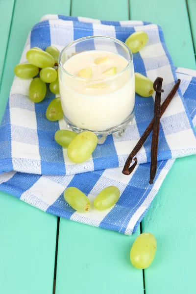 Iogurte delicioso em vidro com uvas na mesa de madeira close-up — Fotografia de Stock