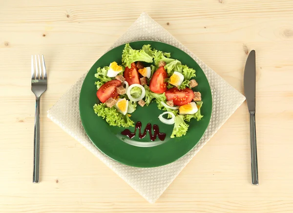 Friss vegyes saláta, tojás, paradicsom, saláta levelek és egyéb zöldségek, a lemez, színes, fából készült háttér — Stock Fotó