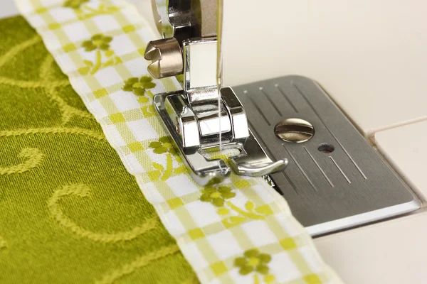 Крупный план швейной машины, работающей с зеленой тканью — стоковое фото