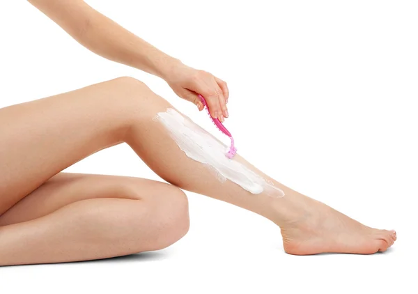 Schöne Frau rasiert sich ihr Bein, isoliert auf weiß — Stockfoto
