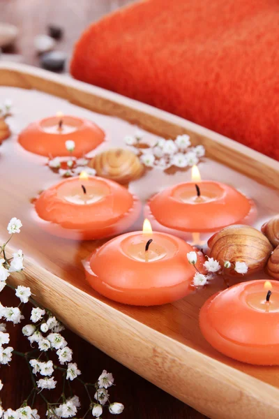 Beautiful candles in water on wooden table on natural background — Stock Photo, Image