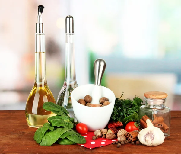 Composition of mortar, bottles with olive oil and vinegar, and green herbals, on bright background — Stock Photo, Image