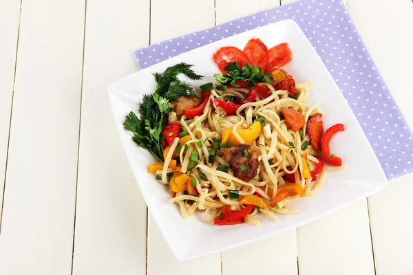 Fideos con verduras en plato sobre mesa de madera — Foto de Stock