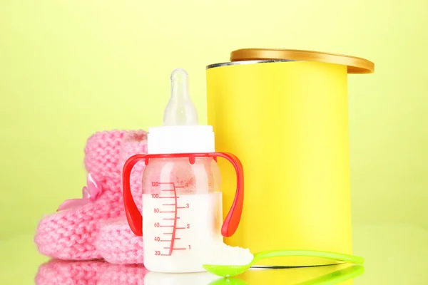 Bottle with milk and food for babies on green background — Stock Photo, Image