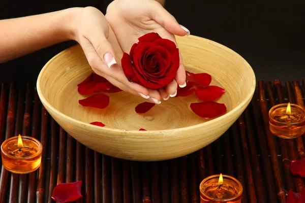 Woman hands with wooden bowl of water with petals — Stock Photo, Image