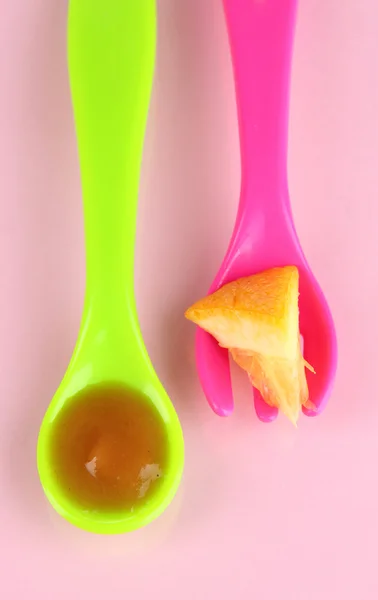 Fourchette et cuillère de couleur pour aliments pour bébés sur fond rose — Photo