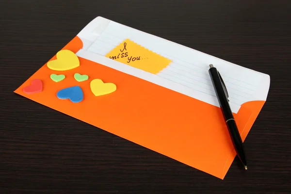 Заметка в конверте с ручкой на деревянном фоне — стоковое фото