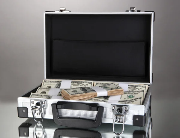 Kufr s 100 dolarové bankovky na šedém pozadí — Stock fotografie