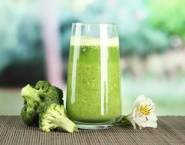 Vaso de jugo de brócoli, sobre estera de bambú, sobre fondo verde — Foto de Stock